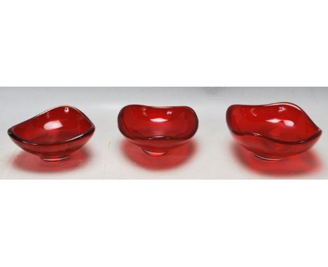 A collection of three retro vintage studio art glass 1970s Whitefriars ruby bowls of triangular form raised on a circular bas