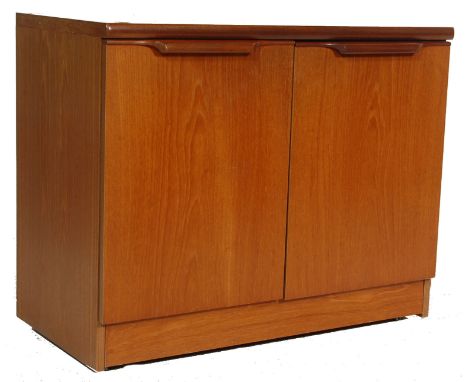 A vintage retro G Plan teak wood low entertainment cabinet having twin doors with lipped handles opening to reveal a sliding 