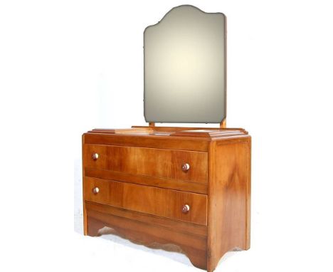 A 20th century Art Deco style walnut dressing table chest having a shaped mirror atop and a bank of two long drawers raised o