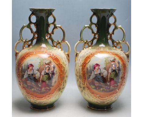 A pair of 19th century Victorian ceramic vases having a green background, flared neck, gilt handles over polychrome panels de