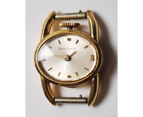 A vintage ladies Jaeger LeCoultre 18ct gold cased cocktail watch having an oval face with a brushed silver face and gilt bato