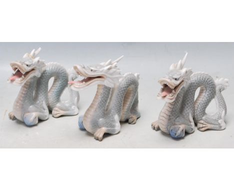 A group of three vintage 20th century ceramic porcelain Chinese dragons of typical form. All are having the front leg raised 
