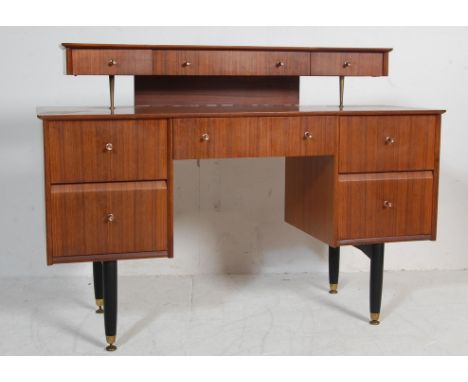 A vintage 1960’s teak wood dressing table desk by Nathan having a suspended top shelf with four short drawers above a kneehol