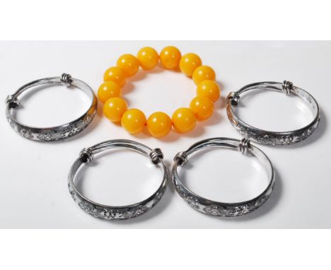 A collection of four chinese white metal bangle /&nbsp; bracelets having floral decoration and Chinese characters to the edge