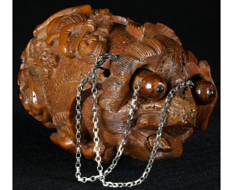 A late 18th/early 19th century coquilla nut 'bug bear', carved with a musician and a portrait roundel, 8.5cm long, c.1800 