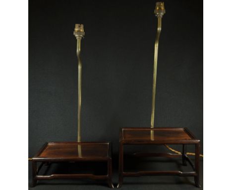 A graduated pair of Chinese hardwood connoisseurs stands, each fitted with a table lamp, rectangular plateaux, shaped stretch