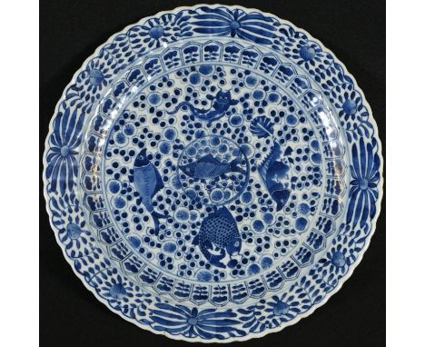 A Chinese shaped circular charger, painted in underglaze blue, the centre with five fish on a stylized scale ground, the bord