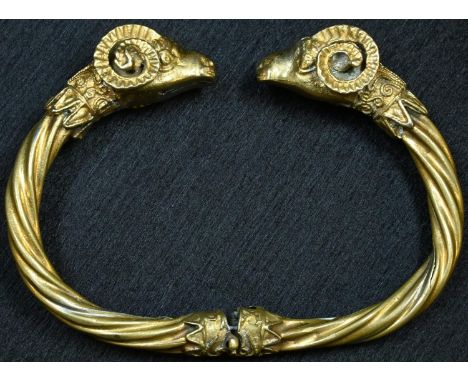 A Grecian Revival gilt metal hinged bangle, terminating in rams' head masks, 8.5cm wide 