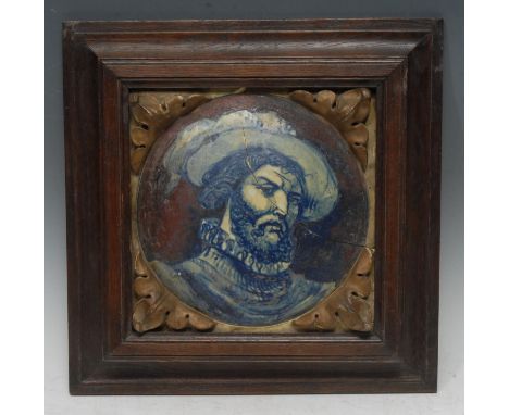 An Italian maiolica panel, painted with a portrait of a bearded gentleman wearing a ruff and a feathered hat, acanthus to ang