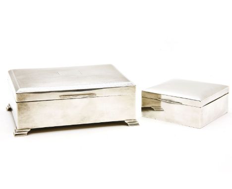 A silver and cedar lined engine turned desk top cigarette box, on short feet, 17cm wide, together with a further smaller silv