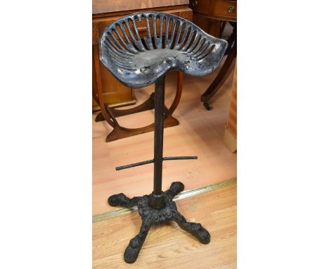 A cast-iron bar/kitchen seat with tractor seat top on an early 20th century cast metal base