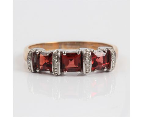 A three stone garnet ring with diamond accents, stamped 375, ring size R.&nbsp;IMPORTANT: Online viewing and bidding only. No