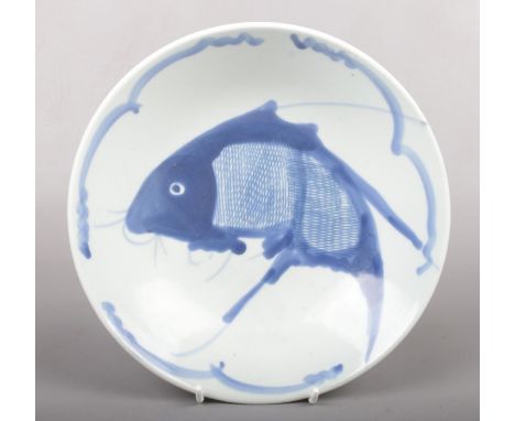 A Chinese Kangxi style blue and white dish. Painted with wide strokes of underglaze blue with a carp under a simple line bord