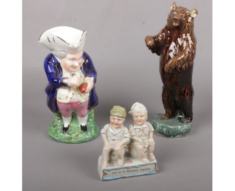 A German Fairing group ' Let us do Business together' figures, to include Staffordshire Toby jug and ceramic bear figure  