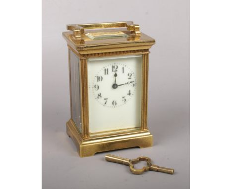 A brass cased carriage clock. With enamel dial and fluted pilasters. Backplate stamped with a lion, 15cm.  Runs only for a sh