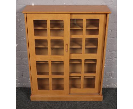 A light oak CD cabinet with glass front sliding doors.  