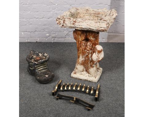 A cast concrete bird bath, along with a concrete boot shaped planter and a fire grill.  