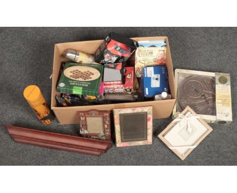A box of miscellaneous household items including boxed Olympus digital camera, photograph frames and a boxed thermometer / cl