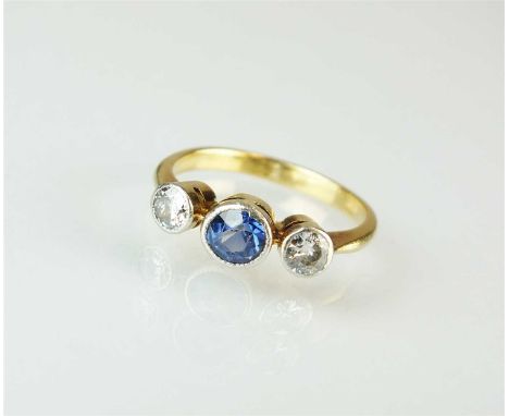 An early 20th century three stone sapphire and diamond ring, designed as a central round mixed cut sapphire flanked to each s