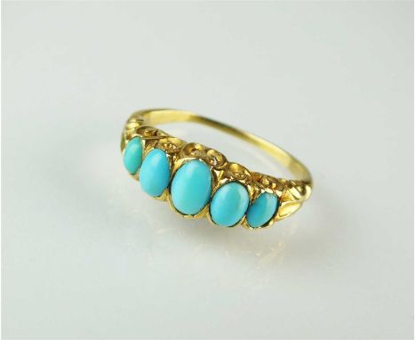 A five stone turquoise ring, the graduated oval turquoise cabochons mounted to carved scroll gallery, the yellow metal shank 