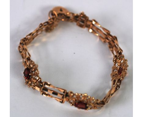 9ct GOLD GATE PATTERN BRACELET, with three fancy links of pierced oval flower pattern, each set with an oval red stone, 8.5gm