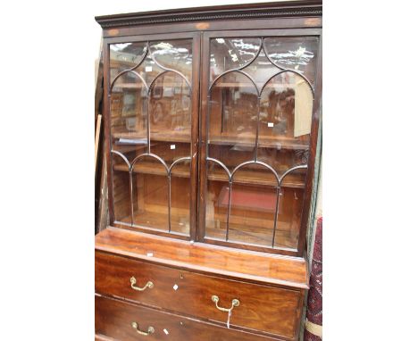 A late George III mahogany bookcase, the Gothic glazed doors opening to reveal shelves, the base section with two large drawe