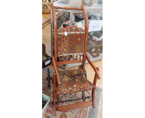 A wooden child's push chair, having tapestry seat and back 