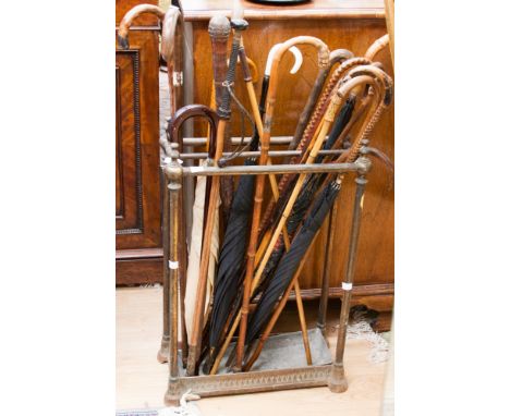 A late Victorian brass stick stand, containing a quantity of assorted walking sticks, umbrellas, riding crops, etc 