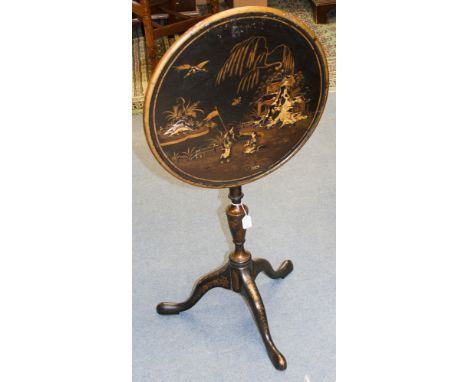 A George III style Chinoiserie black lacquered tripod wine table, circa 1920, the tilting top decorated with an Oriental gard