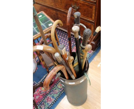 An early 20th Century copper cylindrical stick stand containing a quantity of assorted walking sticks, riding crops, umbrella