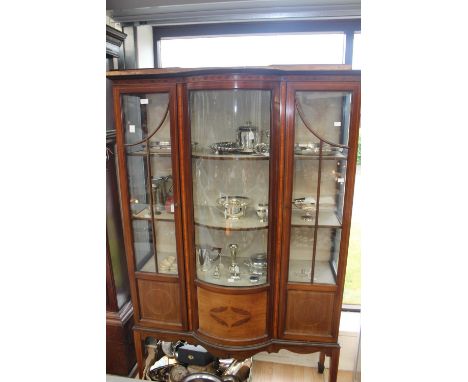 An Edwardian mahogany display cabinet  fitted with two doors and a bow fronted central section and enclosing two shelves, rai