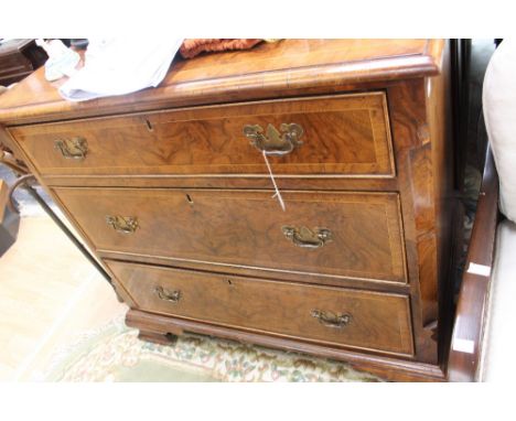 A George I style walnut veneered chest of drawers, fitted with three long graduated drawers, with canted corners, raised on b