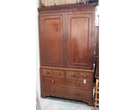 A George III mahogany linen press, circa 1815, fitted with two large doors with rope twist applied decoration, with two short