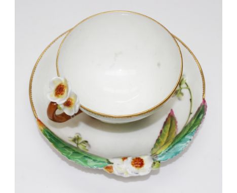 An Aesthetic Movement teacup and saucer by William Brownfield, circa 1875, the cup on three feet realistically modelled as le
