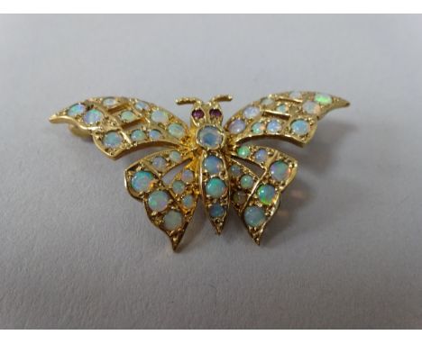 A 9CT GOLD OPAL AND RUBY BUTTERFLY SHAPE BROOCH, with opal stones adorning the wings with ruby eye accents, hallmarks for Lon