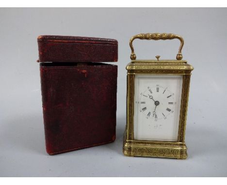 A FRENCH GILT BRASS CARRIAGE CLOCK, with scroll and fleur de lys decoration, white enamel dial having Roman numeral chapter r