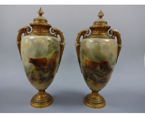 A PAIR OF ROYAL WORCESTER PEDESTAL VASES AND COVERS, the ovoid bodies hand painted with mountainous landscape with highland c