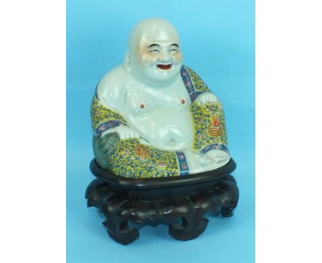 A Chinese porcelain figure of a seated Buddha decorated in famille rose enamels on a yellow background, impressed seal mark t