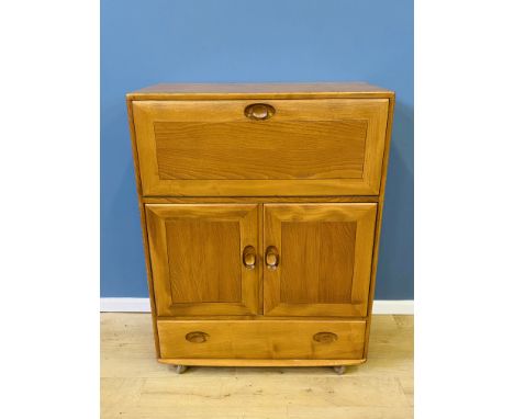 Ercol studio bureau with a fall front, over a pair of doors with drawer below, 82 x 43 x 110cms. Estimate £100-150