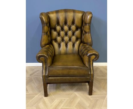 Leather button back wing armchair on square section legs with stretchers, 83 x 73 x 113cms. Estimate £100-150.