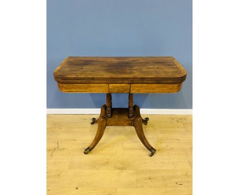 19th century rosewood fold over top card table with white line and crossbanded decoration, on splayed legs with brass castors