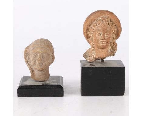 The first a female head raised on a later stand, 9cm high including the stand, the second also raised on a later stand, 6cm h