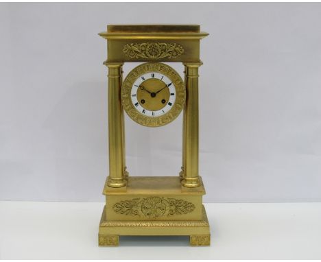 A late 19th Century French Empire gilded four pillar mantel clock with Roman enamelled chapter ring and engine turned centre,