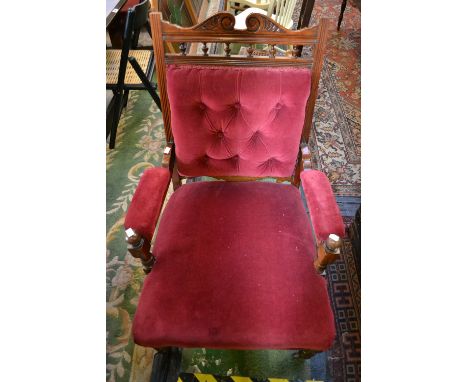 A Victorian mahogany salon armchair, cresting spinled top rail, finials to uprights, button upholstered back, padded arms and