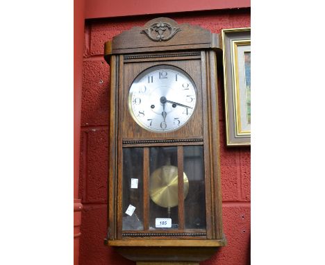An early 20th century oak cased wall clock, key and pendulum
