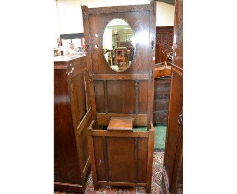 A 1930's oak hall stand, oval mirror flanked by hooks, glove box and stick stand to base.
