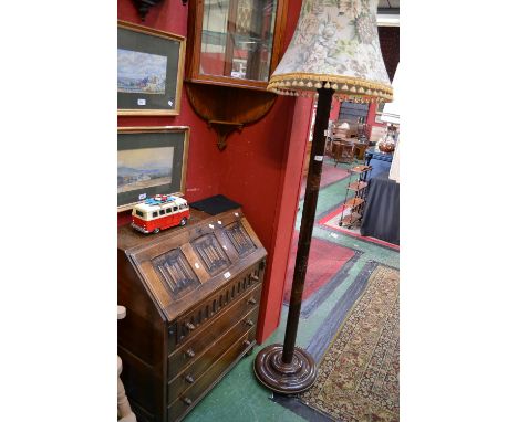 An oak Priory style bureau, three linenfold panels to fall front over four drawers; a standard lamp, the column decorated wit
