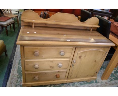 A Victorian pine sideboard, shaped gallery and shelf to back, three drawers and adjacent cupboard to base, turned handles and