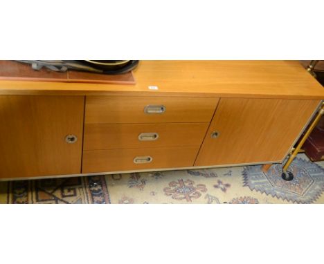 A retro light teak sideboard, three long drawers flanked by cupboards.