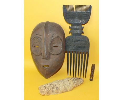 An antique ivory tusk section carved with foliate scrolls, 16cm long, a Polynesian hardwood comb, a small African face mask a